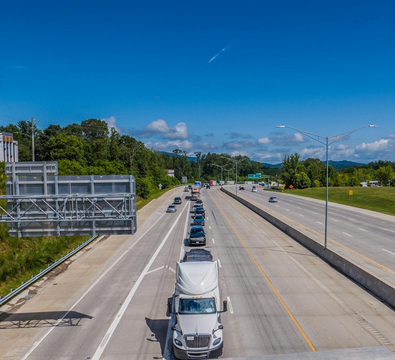 about-us Cars and trucks on a highway under a clear blue sky in daytime